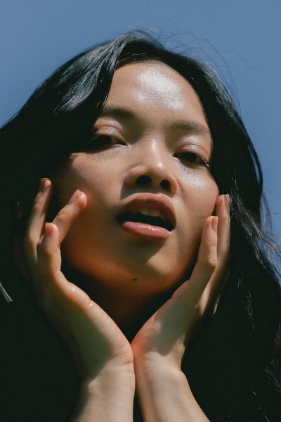 Woman with hands on face against a blue sky