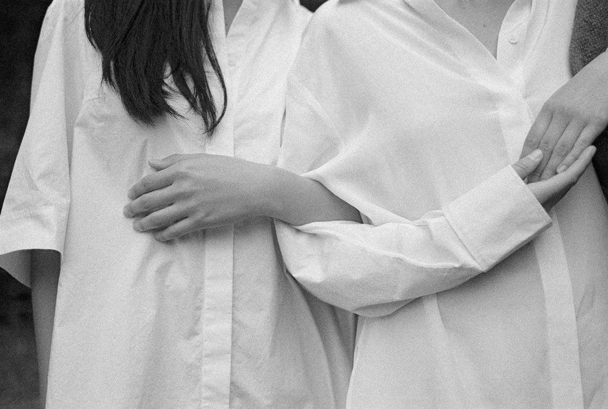 Two people wearing white shirts with their arms around each other, black and white photo.