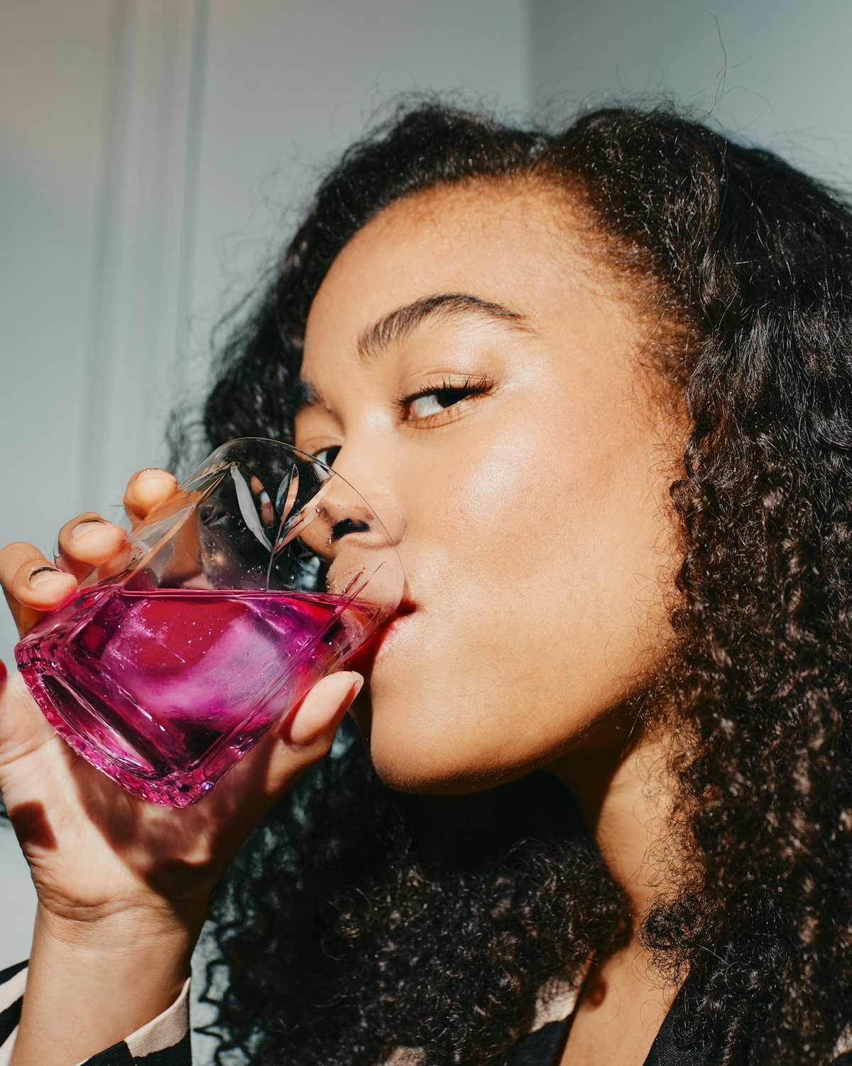 Person drinking from a glass of pink liquid